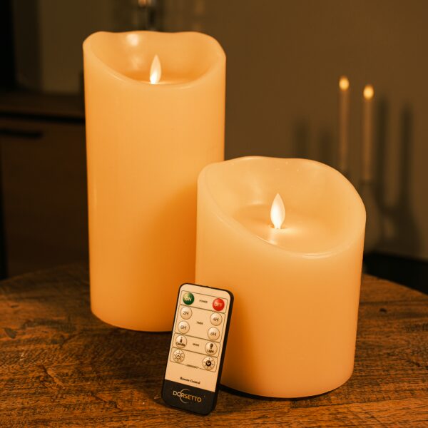 Genopladelige LED-vokslys i varm hvid fra DORSETTO i to størrelser på et træbord med fjernbetjening og hyggelig baggrundsbelysning
