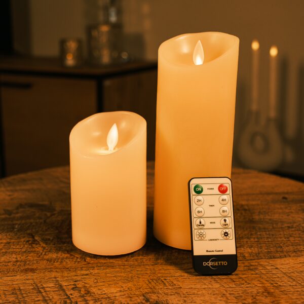 To genopladelige LED-vokslys i forskellige højder fra DORSETTO på et træbord med fjernbetjening og blød stemningsbelysning