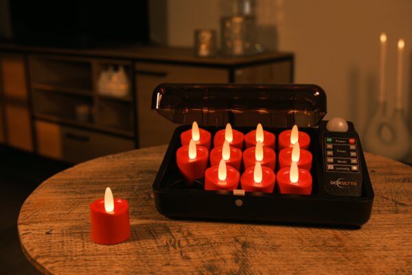 Tolv genopladelige røde LED-fyrfadslys står til opladning i en sort opladecase på et træbord; ét rødt lys ligger adskilt. Den hyggelige stue i baggrunden er dæmpet oplyst.