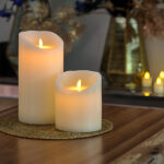 LED-vokslys i varm hvid fra DORSETTO med buede toppe på gylden flettet dækkeserviet omgivet af dekorationer for en varm stemning