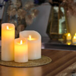 Genopladeligt LED-vokslys med bevægelig flamme i varm hvid på flettet måtte med dekorative elementer i baggrunden