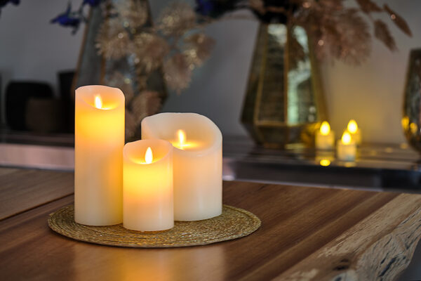 Genopladeligt LED-vokslys med bevægelig flamme i varm hvid på flettet måtte med dekorative elementer i baggrunden