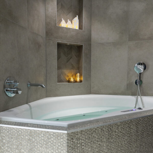 een driehoekig bubbelbad met verschillende waxinelichtjes in de muur