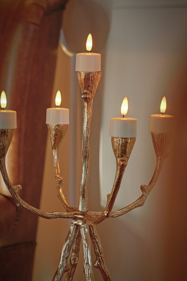 Een goudkleurige kandelaar met vijf brandende witte kaarsen is perfect voor LED waxinelichtjes met bewegende vlam (brandtijd 175 uur, oplaadbaar, afstandsbediening, timerfunctie, 6 stuks) om een uitnodigende en elegante sfeer binnenshuis te creëren.