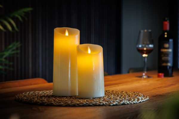 To genopladelige LED-vokslys fra DORSETTO på en flettet dækkeserviet med vin og blødt oplyst baggrund for en hyggelig atmosfære