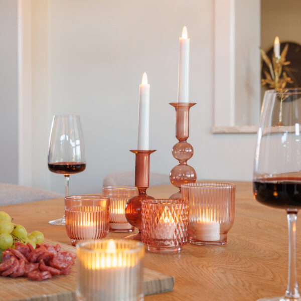 verschillende kaarsen met wijnglazen en borrelplank op een tafel