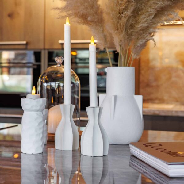 Twaalf 3D oplaadbare LED-thee/waxinelichtjes (175 uur, met afstandsbediening en timerfunctie) in witte houders staan op een marmeren tafel naast een witte kan met pampagras, een glazen stolp en een boek in een moderne keuken.