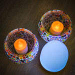 een blauwe bol met 2 waxinelichtjes in gekleurde potjes