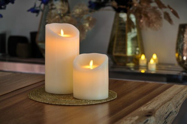 2 kaarsen van dorsetto op een onderzetter op tafel met op de achtergrond meer kaarsen en bloemen