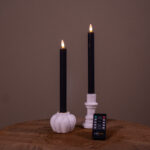 To genopladelige LED-dinerlys (sæt med 2, 400 timers brændetid) placeret i hvide lysestager – én græskarformet og én cylindrisk – på en træoverflade med en fjernbetjening foran, mod en ensfarvet baggrund.