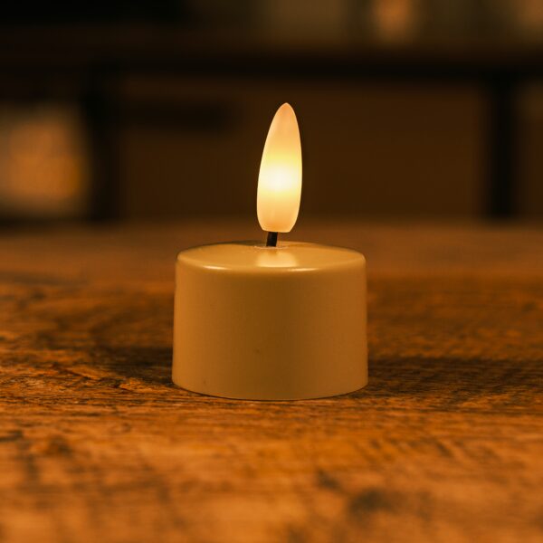 Lille LED-lys med varm, glødende flamme placeret på en træoverflade og skaber en hyggelig stemning