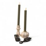 To grønne LED-dinerlys med cremefarvede holdere står på en hvid baggrund sammen med en sort fjernbetjening og en sort strømadapter. Lysene har flammeformede LED-toppe.