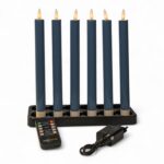 Seks mørkegrå LED-dinerlys på 250 mm i en sort lysestage. Sættet er genopladeligt, dæmpbart og udstyret med timerfunktion. Foran lysene ligger en fjernbetjening og en strømadapter, alt præsenteret på hvid baggrund.