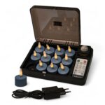 En sort opladeboks med 12 blå genopladelige fyrfadslys (Stone Bleu No.86, brændetid op til 400 timer), en fjernbetjening, ét fyrfadslys uden for boksen samt en sort strømadapter og kabel foran – på en hvid baggrund.